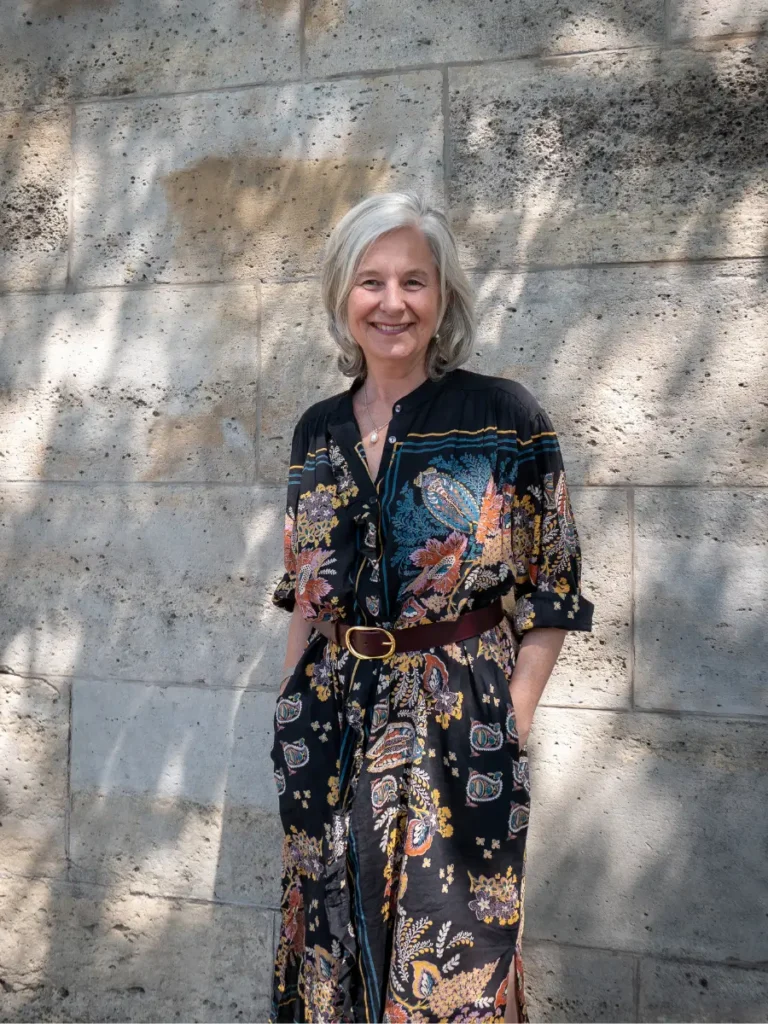Portrait de Catherine Chavigny devant un mur en pierre, illustrant son parcours de coach professionnelle et son expérience du monde de l'entreprise.